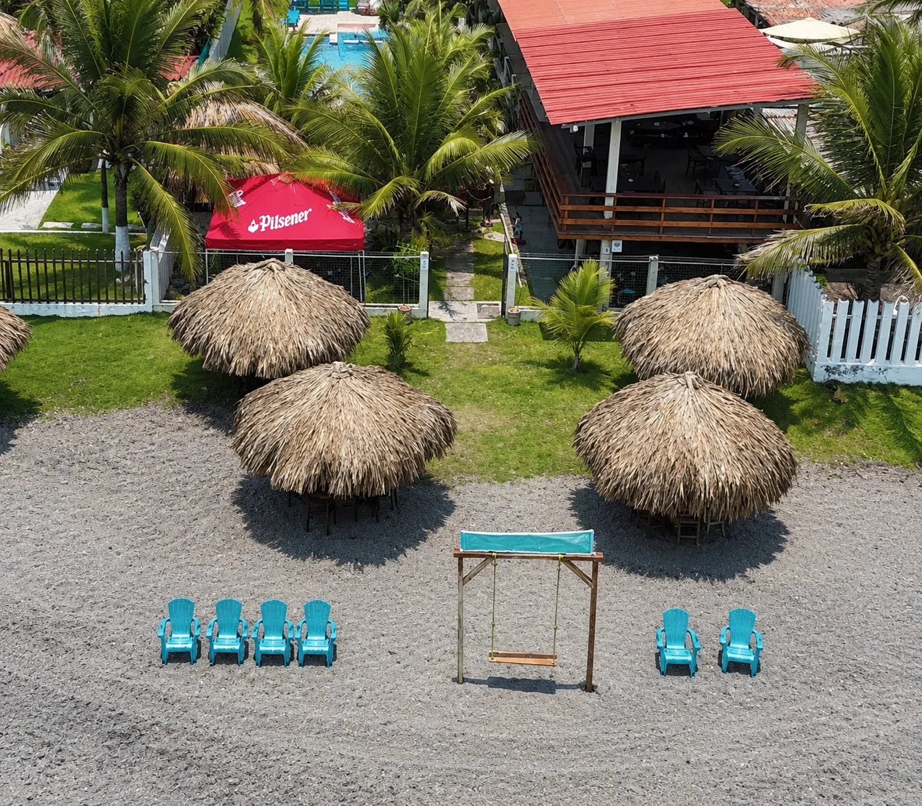 Terraza y palapas frente a la playa, con hamacas y sombrillas de palma