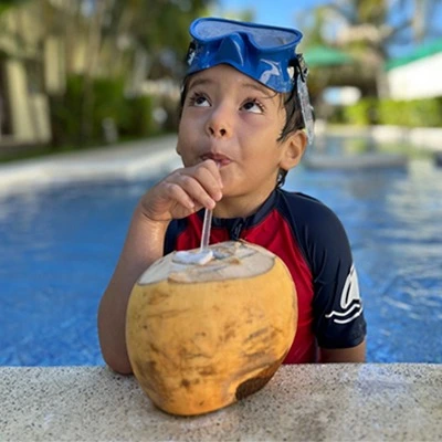 Niño disfrutando de un coco con snorkel en la piscina