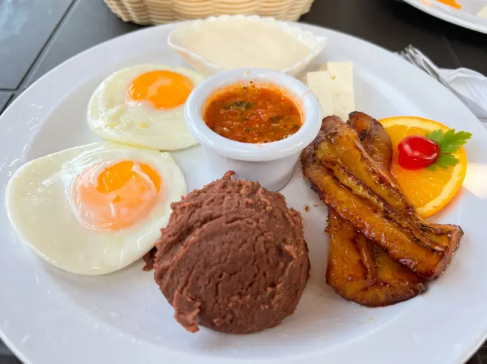 Desayuno típico salvadoreño con huevos, frijoles, plátano y queso