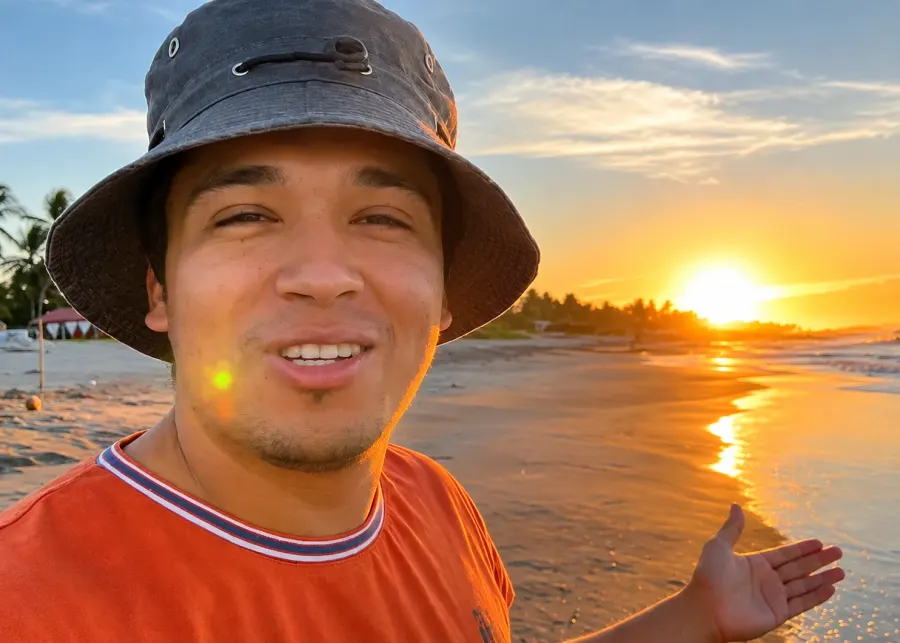 Vlogger con sombrero al atardecer en la playa del hotel